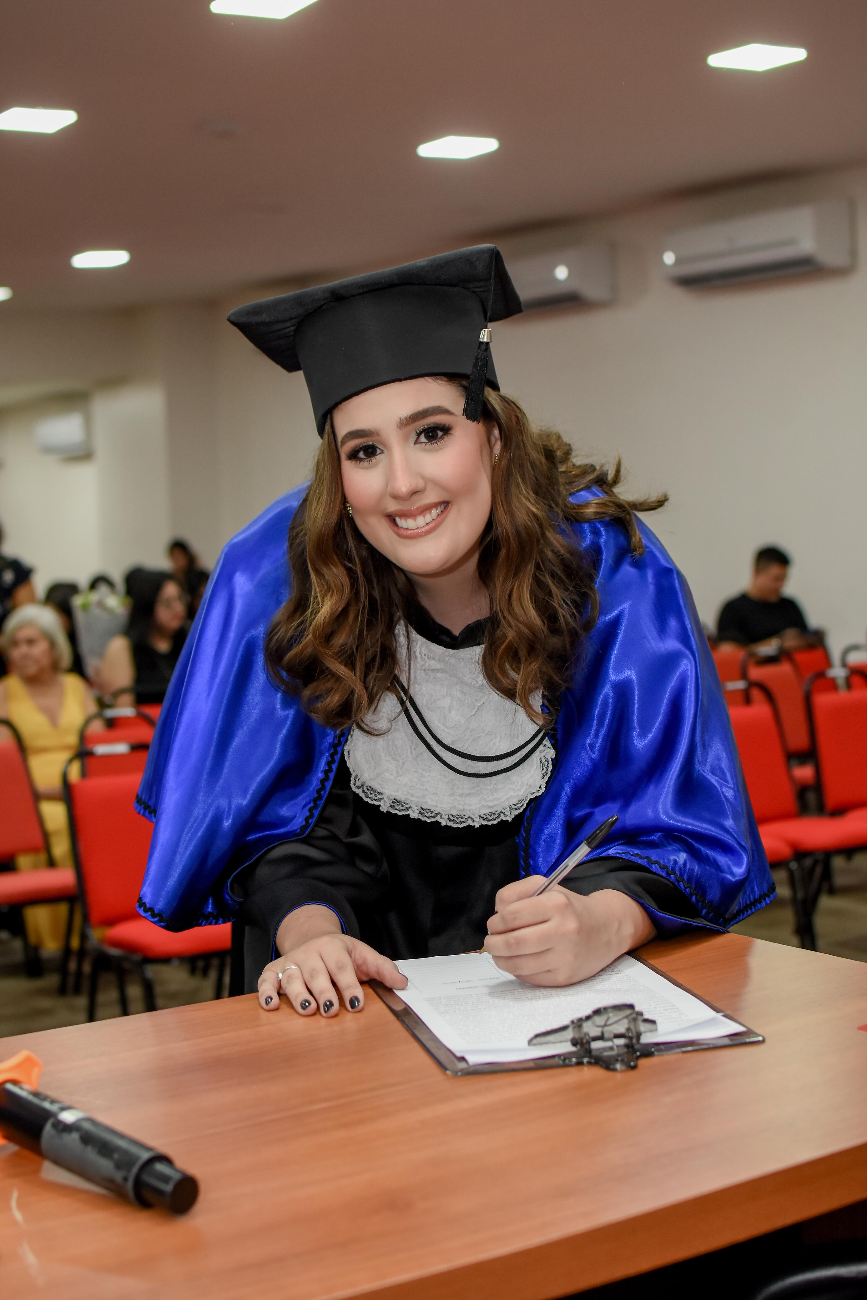Bianca Mesquita em sua formatura, assinando o diploma