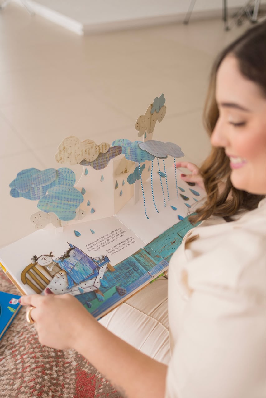 Bianca Mesquita com um livro pop-up infantil